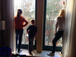 Backs of three people silhouetted against a large window