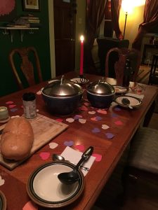 a set table with one candle and paper hearts spread across it