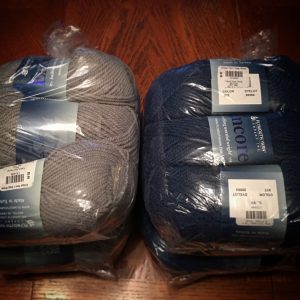 a picture of skeins of yarn in gray and blue, wrapped in plastic